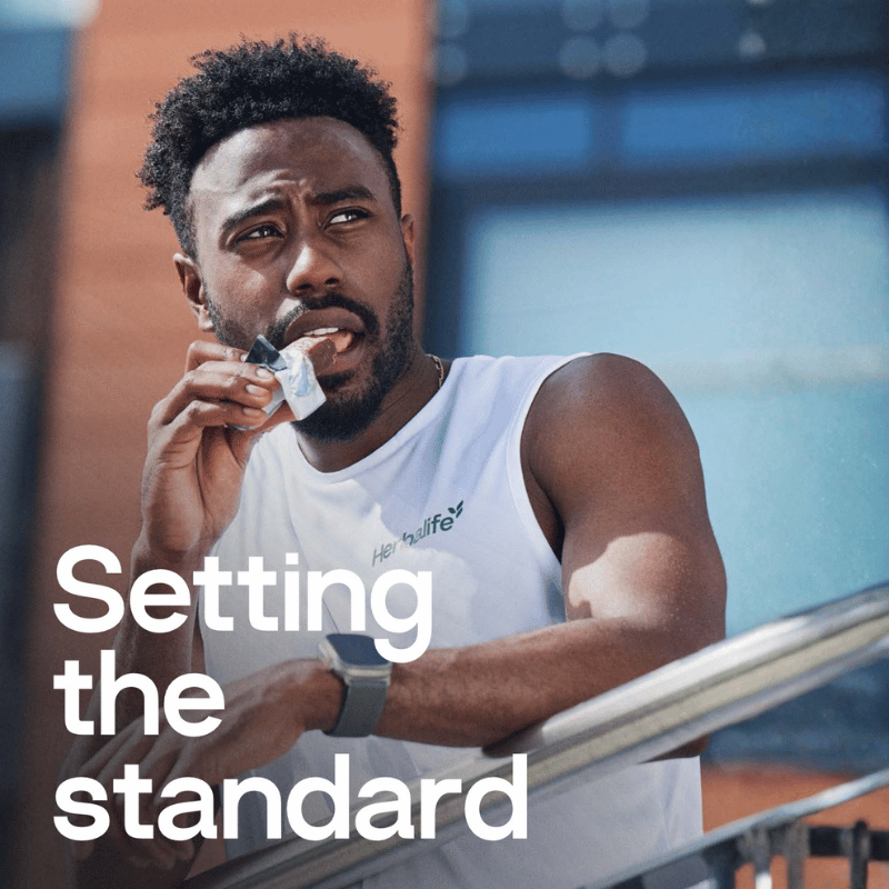 Man in a white tank top with 'Himalife' logo, holding a supplement, with text 'Setting the standard'.
